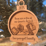 Personalized wooden Christmas ornament engraved with “These are a few of our favorite things,” featuring custom icons, the year 2025, and the Sarpangal Family name hanging on a Christmas tree.