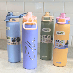 Four Ello 22oz stainless steel water bottles in pastel colors (blue, purple, green, and peach) sitting on a countertop, with one personalized name engraving shown.