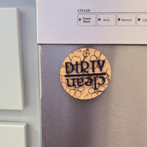 Wooden dishwasher magnet sign on stainless steel dishwasher showing “Dirty” with floral engraved design.