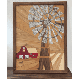 Framed rustic farmhouse wall art featuring a wooden windmill, red barn, and rolling fields made from layered natural hardwoods and metal accents.