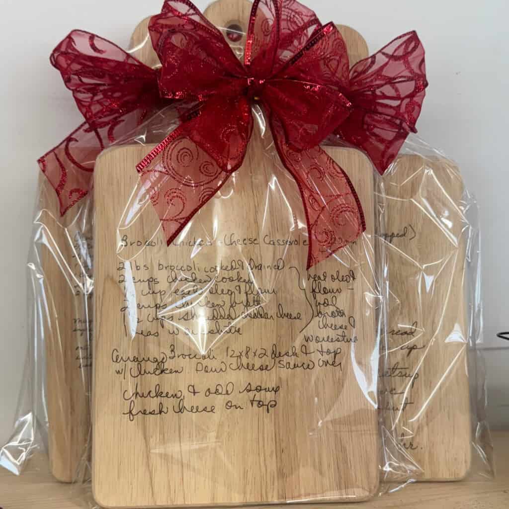 engraved wooden recipe cutting boards wrapped in clear cellophane with red ribbon bows and handwritten family recipes