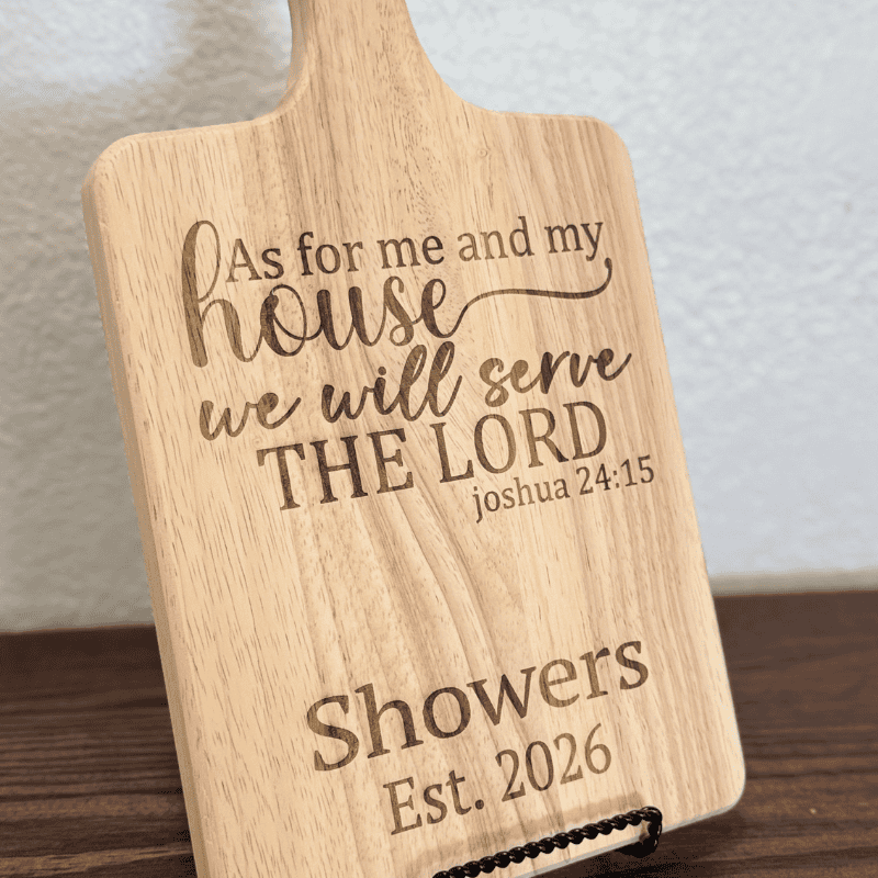 close up of engraved wooden cutting board with as for me and my house we will serve the lord joshua 24 15 and personalized family name