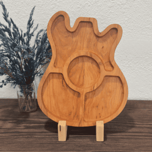 Guitar shaped wooden charcuterie board with divided sections on rustic table