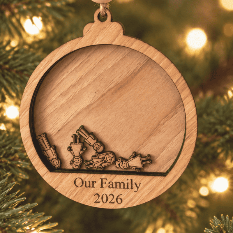 Wooden family ornament hanging on a Christmas tree, featuring little wooden people against a plain wood background and “Our Family 2026” at the bottom.